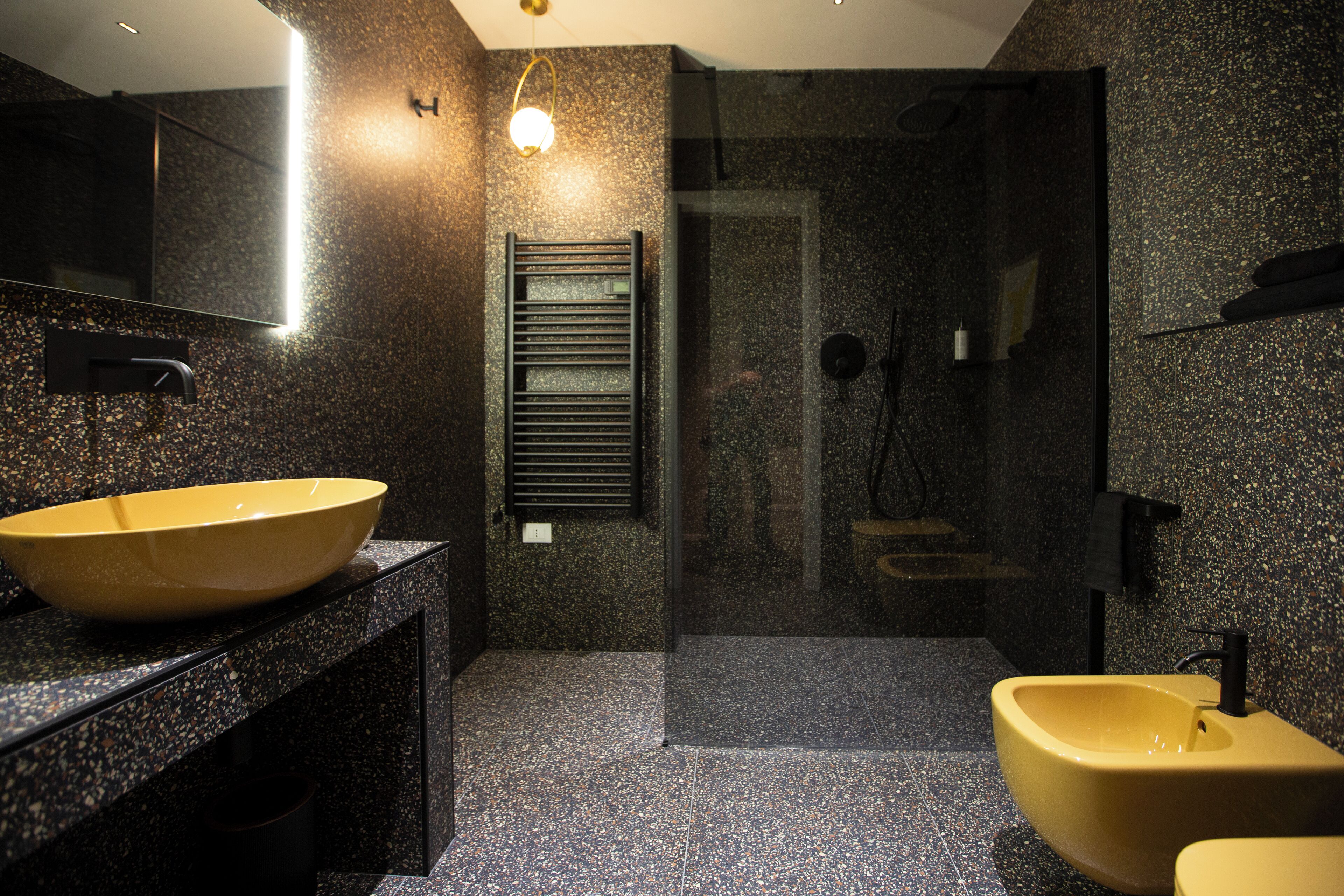 Ein modernes Badezimmer mit einem großen, gelben Waschbecken, einem Spiegel und einer Duschkabine.