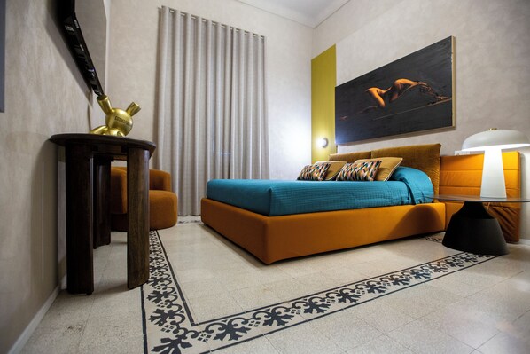 A modern hotel room with a large bed, a desk, a lamp, and a painting on the wall. - Reverse Art Hotel (Vasto)