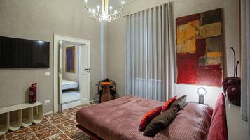 Ein Schlafzimmer mit einem großen Bett, einem an der Wand befestigten Fernseher, einer Kandelaberleuchte und einem Gemälde.