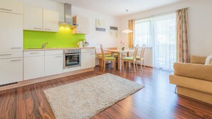 A modern kitchen with white cabinets, a green backsplash, and a dining area with a wooden table and chairs. - The apartments are located in a quiet and central area—ideal for families (Flachau)