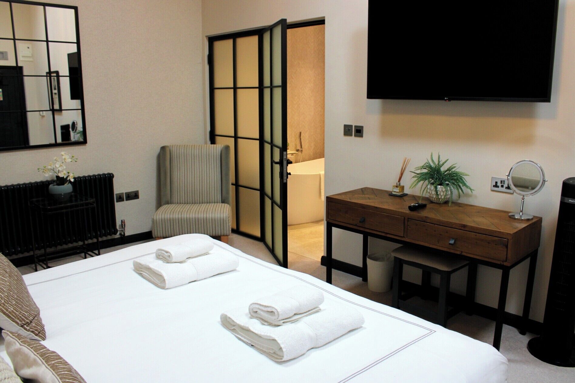 A hotel room with a bed, a desk, a chair, a TV, and a sliding door.