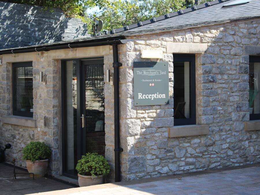 A stone building with a reception sign, windows, and potted plants.