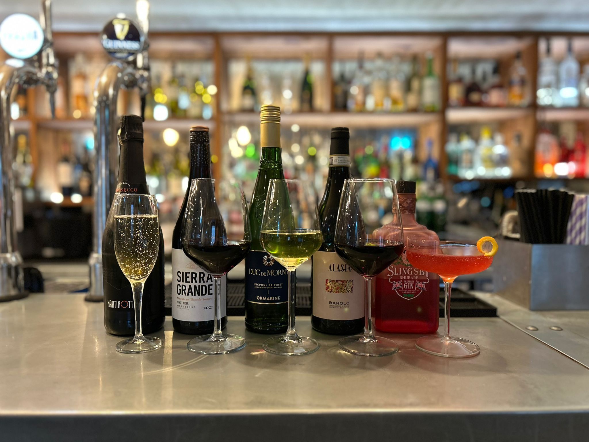 A bar with various bottles and glasses of wine and cocktails.