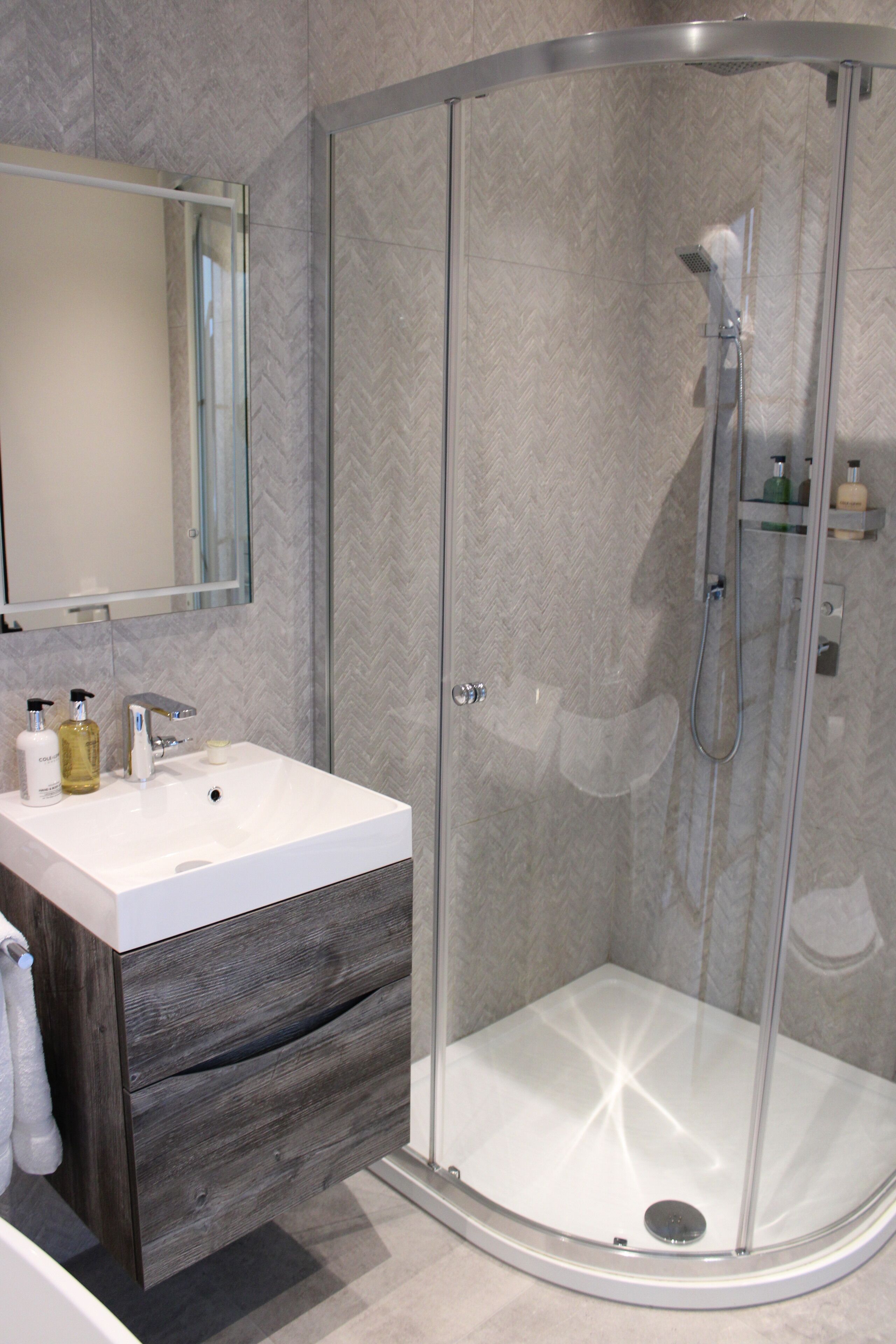 A modern bathroom with a glass-enclosed shower, a white sink, and a mirror above it.