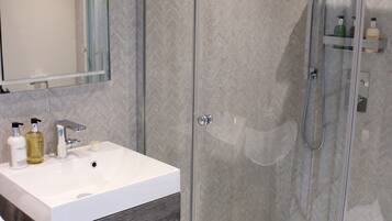 A modern bathroom with a glass-enclosed shower, a white sink, and a mirror above it.