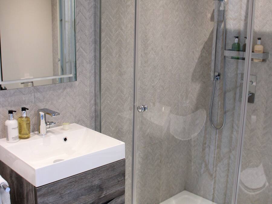 A modern bathroom with a glass-enclosed shower, a white sink, and a mirror above it.