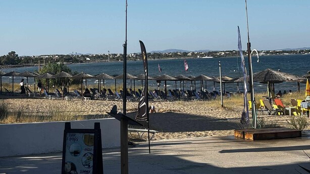A beachside area with sun loungers, umbrellas, and a signboard advertising beer, drinks, and cocktails. - Beachfront  • 4 Guests • Fast WiFi • AC • Near Airport – Artemis Blue Escape (Artemis)