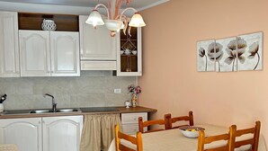 Una cocina con armarios blancos, una mesa de comedor con mantel naranja y una lámpara de araña.