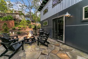 Une terrasse avec un sol en pierre, un foyer et deux fauteuils Adirondack.