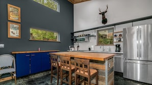 Une cuisine moderne avec un îlot central en bois, des armoires bleues et une tête de cerf fixée au mur.