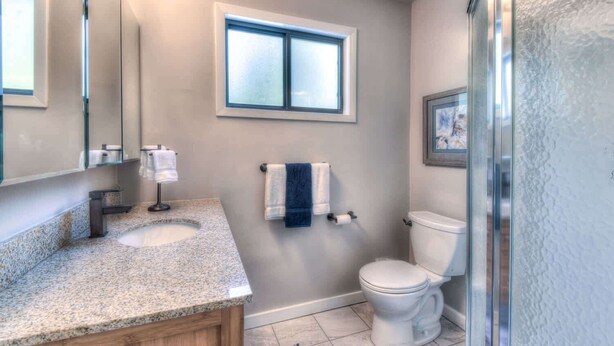 A bathroom with a granite countertop, a double sink, a toilet, and a window. - Moose Manor With BBQ - Near Tahoe Hiking! (Tahoma)