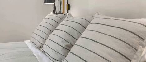 Ein Bett mit weißer Bettwäsche und zwei Kissen mit Streifen.