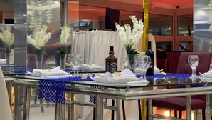Una mesa de comedor dispuesta con servilletas blancas, copas de vino y una botella de whisky Jack Daniel's.