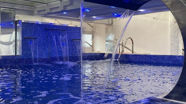 Una piscina con fuente, paredes de azulejos y una estructura de arco de metal.