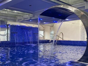 Una piscina con fuente, paredes de azulejos y una estructura de arco de metal.