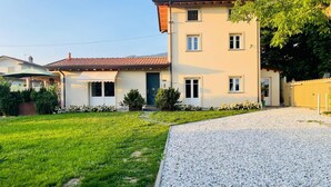 A two-story house with a front porch, a gravel driveway, and a well-maintained lawn. - Villa Francesca, pool (Capanne-Prato-Cinquale)