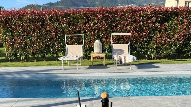 A poolside table with a bottle of champagne, two glasses, and a basket with fruit. - Villa Francesca, pool (Capanne-Prato-Cinquale)