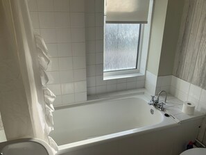 A bathroom with a bathtub, a window, and a toilet. - Ratcliffe House (Sileby)