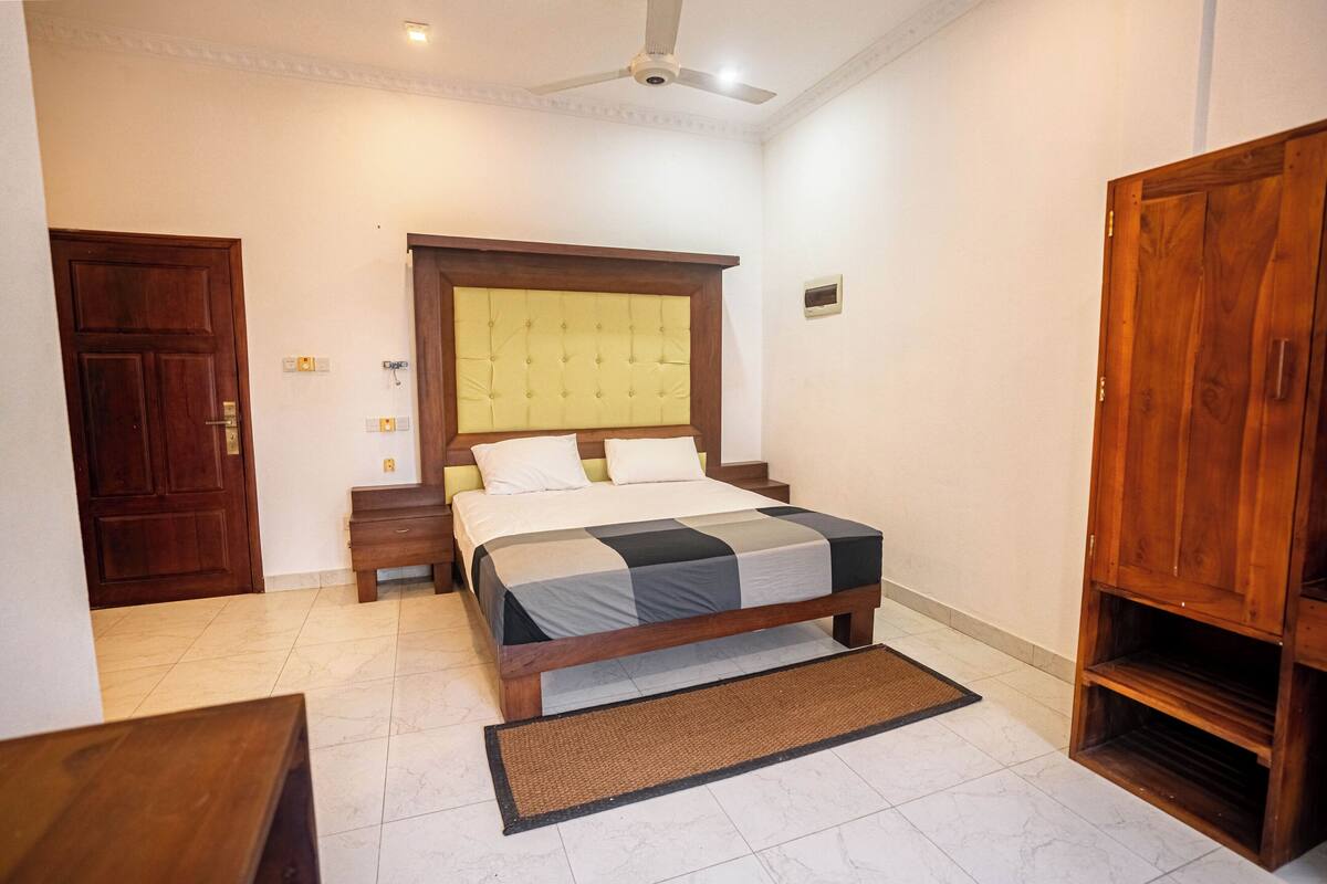 Ein Schlafzimmer mit Bett, Holzschrank und Deckenventilator.