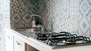 Een keuken met een gasfornuis, een spoelbak en betegelde spatwand.