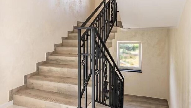 A staircase with a black metal railing leading to a landing with a small window. - Apartamenty Kościuszki 30 Zabrze (Zabrze)