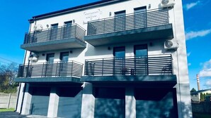 A modern two-story building with balconies, a sign indicating it is a residential apartment, and a clear blue sky in the background. - Apartamenty Kościuszki 30 Zabrze (Zabrze)