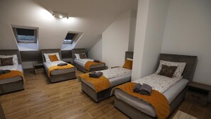 A modern, compact room with three beds arranged in a U-shape, each with a headboard and a small bedside table. - Apartamenty Kościuszki 30 Zabrze (Zabrze)