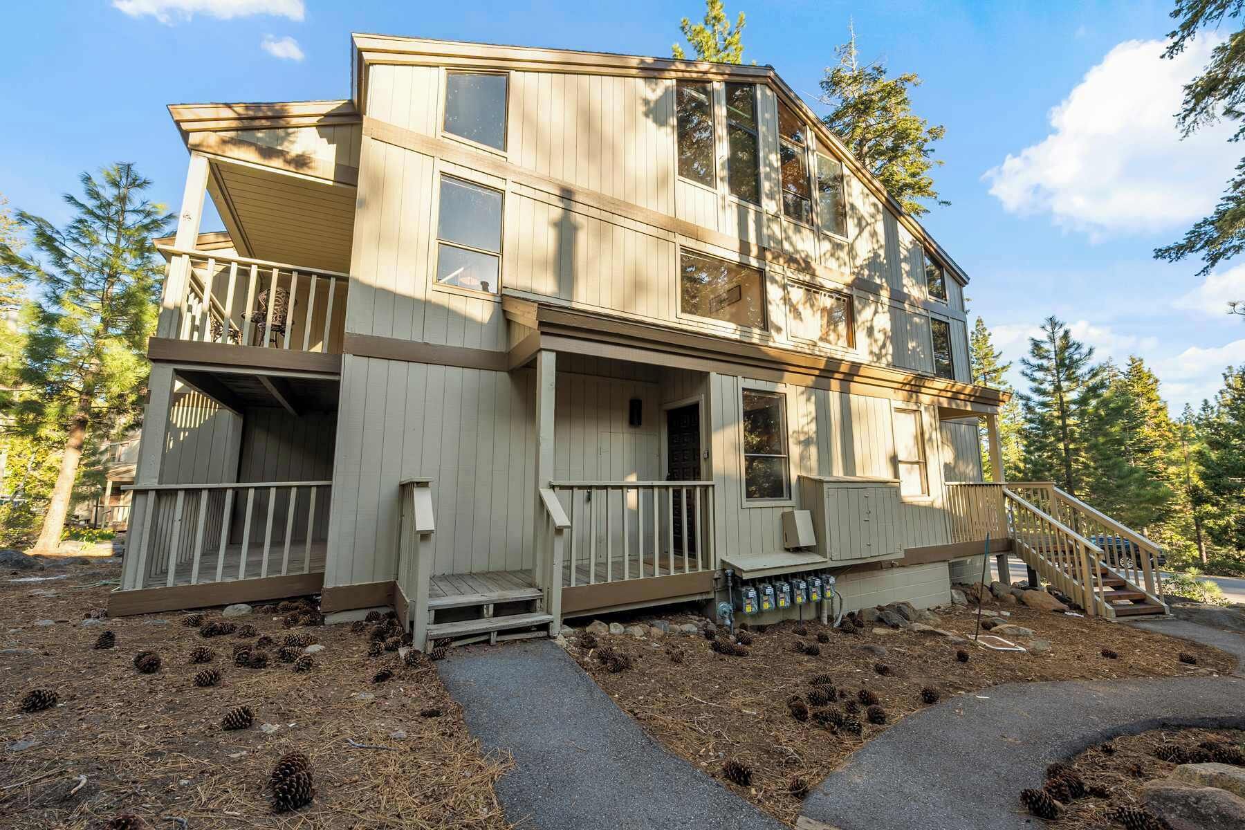 A two-story wooden house with a balcony, a porch, and a staircase leading to the upper level.