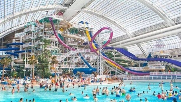 A large indoor water park with multiple slides and pools. - Urban Opulence Loft | Rogers Place | UG Parking (Edmonton)