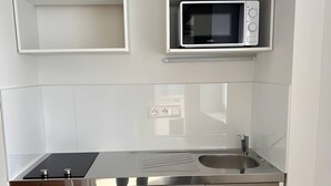 Una cocina compacta con refrigerador, microondas, pileta y alacenas.