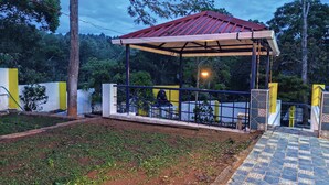 A covered outdoor area with a metal roof, surrounded by a fence and a tiled walkway.