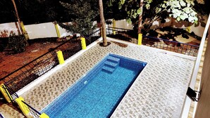 A swimming pool with a tiled deck and a metal fence.
