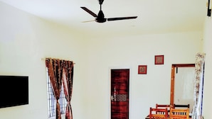 A spacious bedroom with a large bed, a ceiling fan, a wooden nightstand, and a bedside table with a lamp.