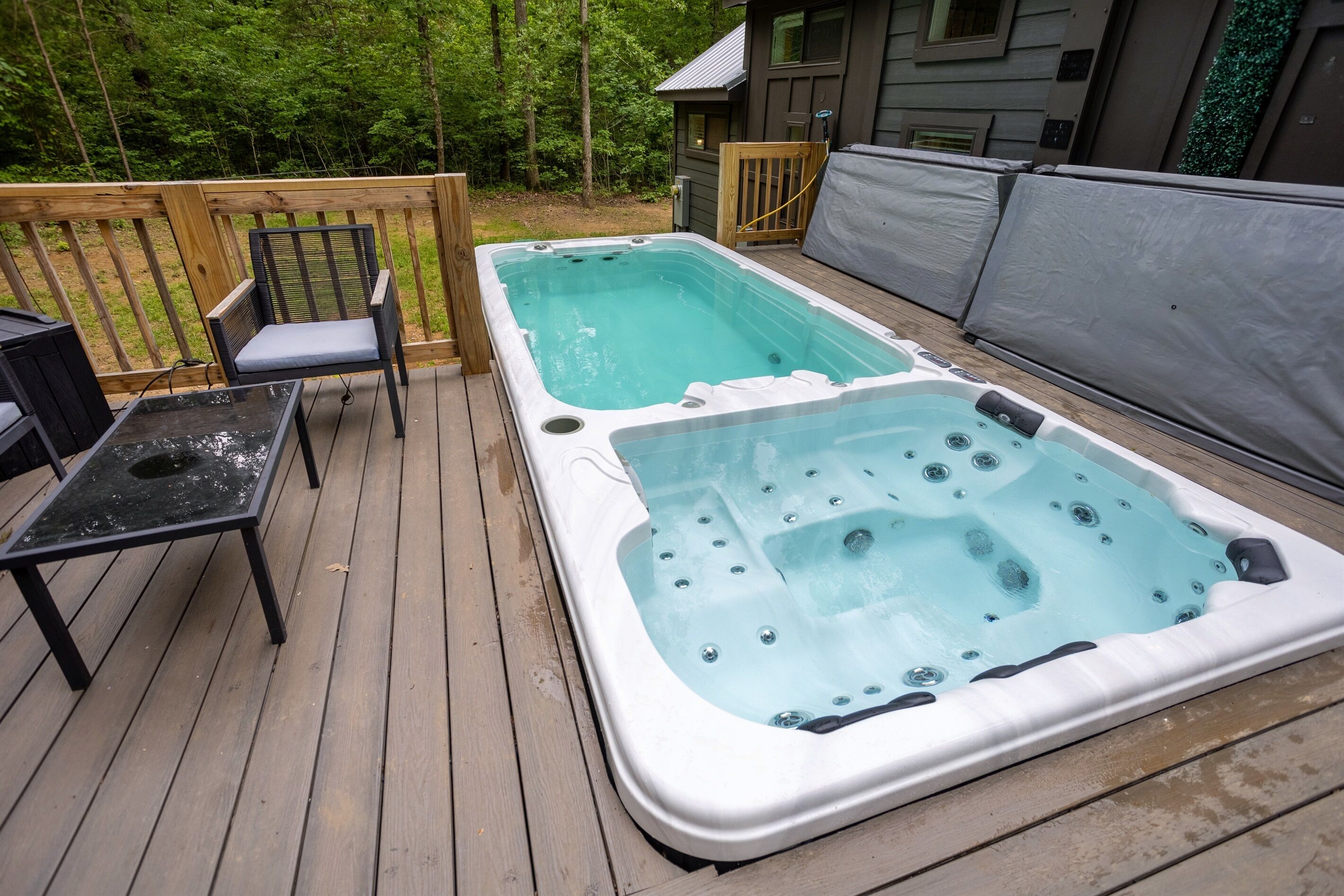 A wooden deck with two hot tubs and a table.