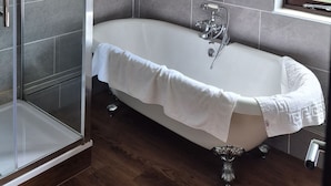 Une salle de bain moderne avec une baignoire sur pieds, une douche à parois de verre et une fenêtre laissant entrer la lumière naturelle.