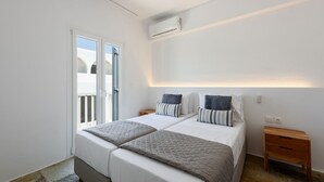 Un dormitorio con una cama, mesitas de noche, un climatizador y una puerta corrediza de vidrio.