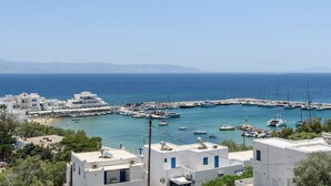 Un pueblo costero con edificios blancos, un puerto deportivo con barcos y una vista despejada al mar.