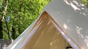 A tent with a bed, a patterned rug, and a lantern. - Evasion Nature Home & Glamping (Grayan-et-l'Hôpital)