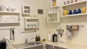 A kitchen with striped curtains, a sink, and various kitchen items on shelves. - Evasion Nature Home & Glamping (Grayan-et-l'Hôpital)