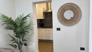 A modern kitchen with white cabinets, a stainless steel range hood, and a round woven mirror on the wall. - VV LAS ARENAS Renovated Apartment in Puerto de la Cruz (Puerto de la Cruz)