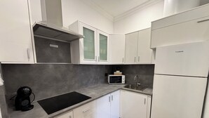 A modern kitchen with white cabinets, a black induction cooktop, a microwave, and a stainless steel sink. - VV LAS ARENAS Renovated Apartment in Puerto de la Cruz (Puerto de la Cruz)