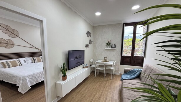 A modern hotel room with a bed, a TV, a dining area, and a sofa. - VV LAS ARENAS Renovated Apartment in Puerto de la Cruz (Puerto de la Cruz)