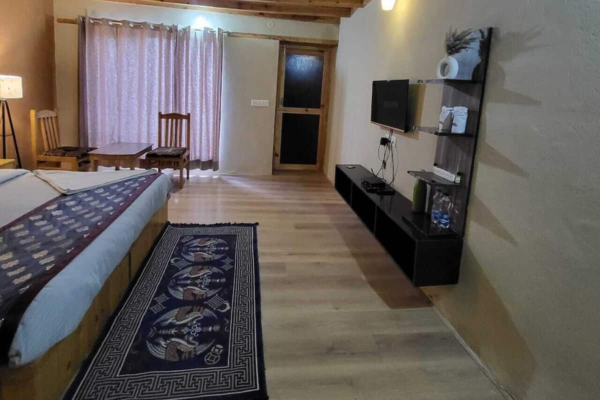 A room with a bed, a TV, a desk, and a chair.
