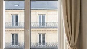 A room with a window overlooking a building with balconies and barred windows. - 1549 Anjou (Paris)