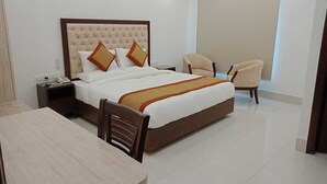 Een hotelkamer met een groot bed, nachtkastje, stoel en bureau.