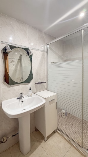 Un baño con lavabo, espejo y ducha.