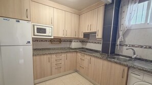 Una cocina con armarios de madera, microondas, lavavajillas Bosch y encimera de granito.
