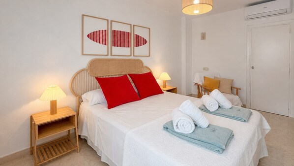 Habitación de hotel con cama, dos mesitas de noche con lámparas, un armario y una obra de arte en la pared.