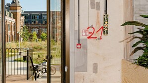 Un interior moderno con un amplio ventanal que da al exterior, un banco de madera y elementos estructurales a la vista.