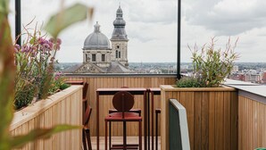 Una terraza de madera con vistas a un edificio histórico con cúpulas y una torre del reloj.